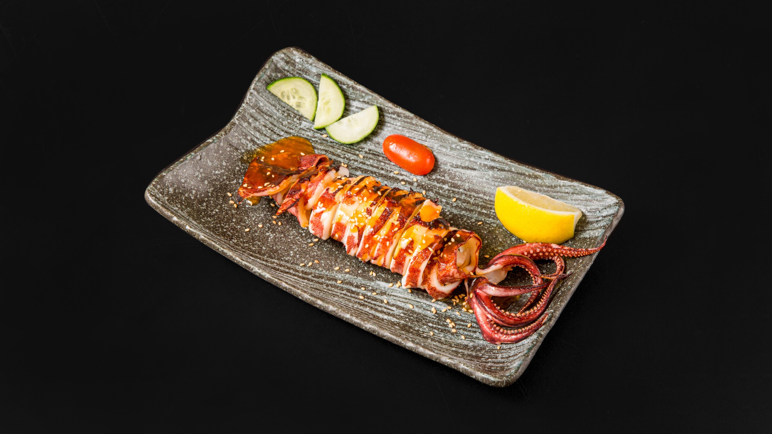 Whole grilled squid with sesame seeds, lemon, cucumber, tomato at Wafuu Izakaya, a Japanese Restaurant in Forest Hills